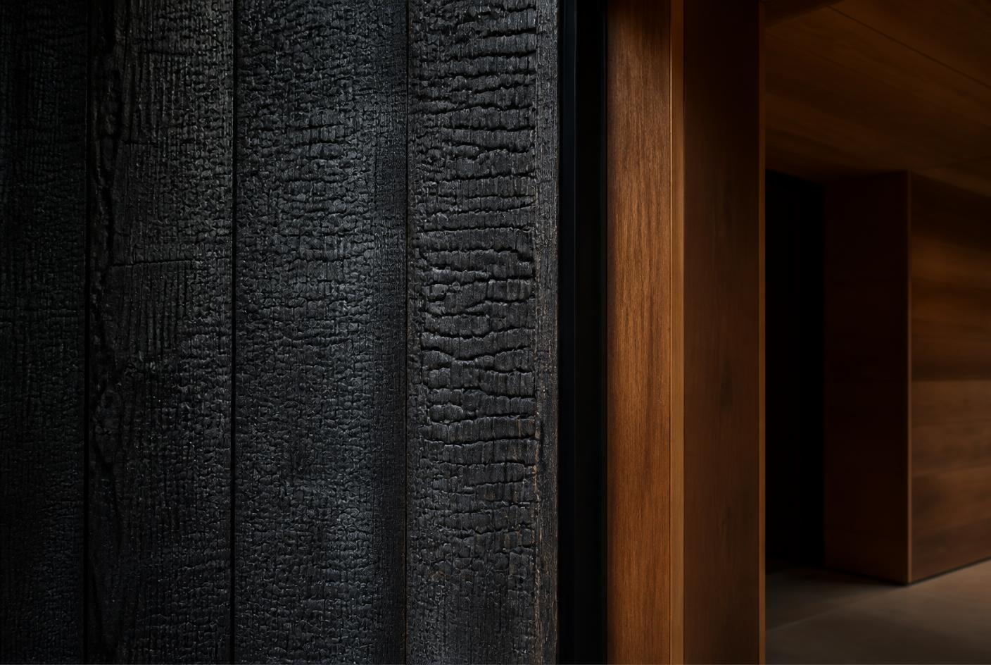 Charred black timber cladding meeting warm oiled interior timber
